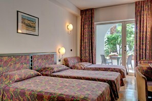 Habitación de hotel con dos camas, una mesa, sillas y vistas al exterior.