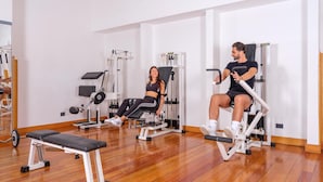 Un gimnasio con equipo de ejercicio, suelo de madera y paredes blancas.