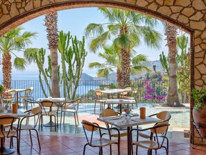 An outdoor dining area with tables and chairs, overlooking a pool and a view of the sea. - Olimpo & Le Terazze (Letojanni)