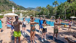A group of people exercising by a poolside with a mountainous backdrop. - Olimpo & Le Terazze (Letojanni)