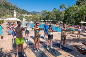 A group of people exercising by a poolside with a mountainous backdrop. - Olimpo & Le Terazze (Letojanni)