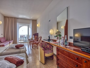 A hotel room with a bed, a desk with a television, a chair, and a view of the outdoors. - Olimpo & Le Terazze (Letojanni)