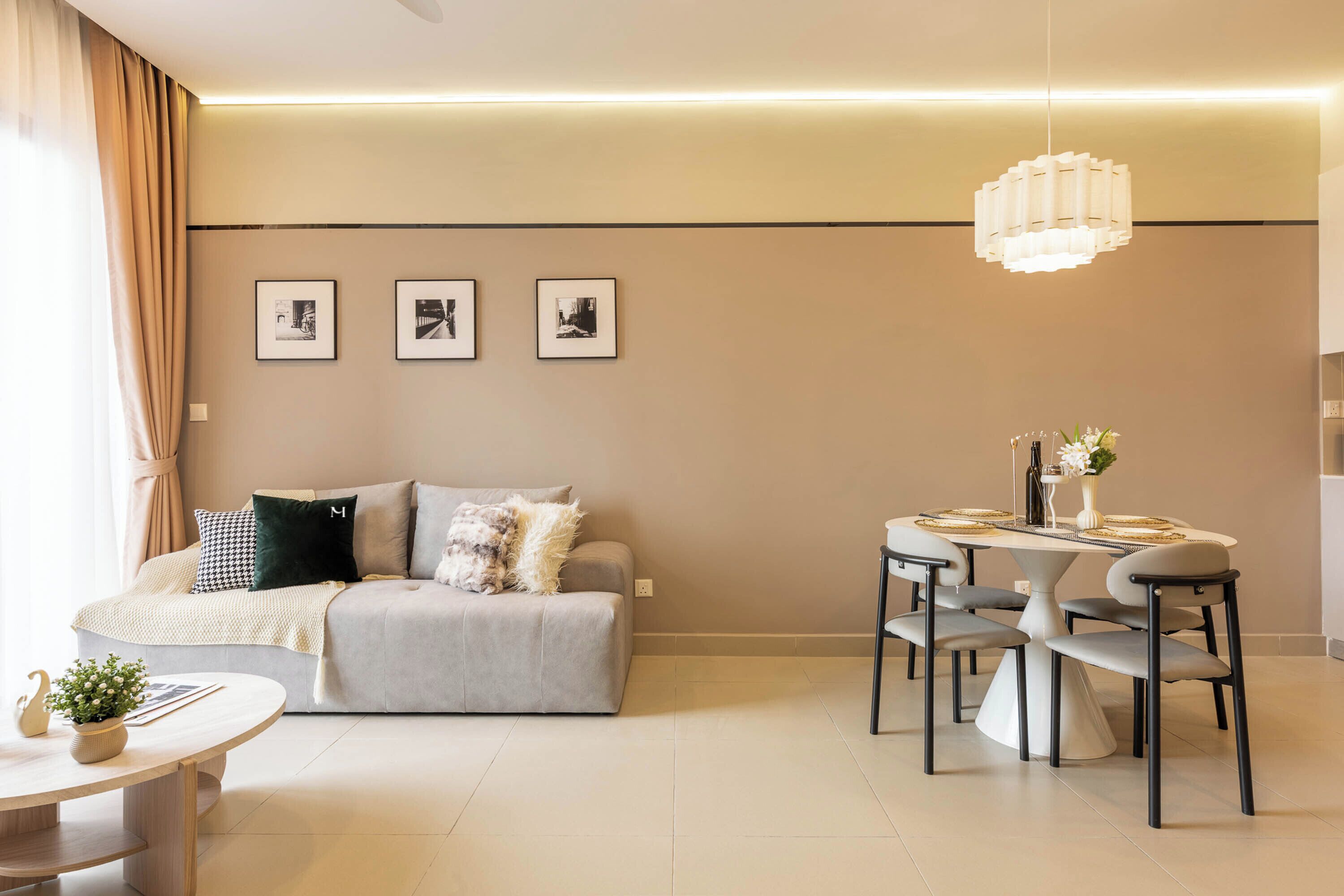 A modern living room with a sofa, a dining table with chairs, and three framed pictures on the wall.