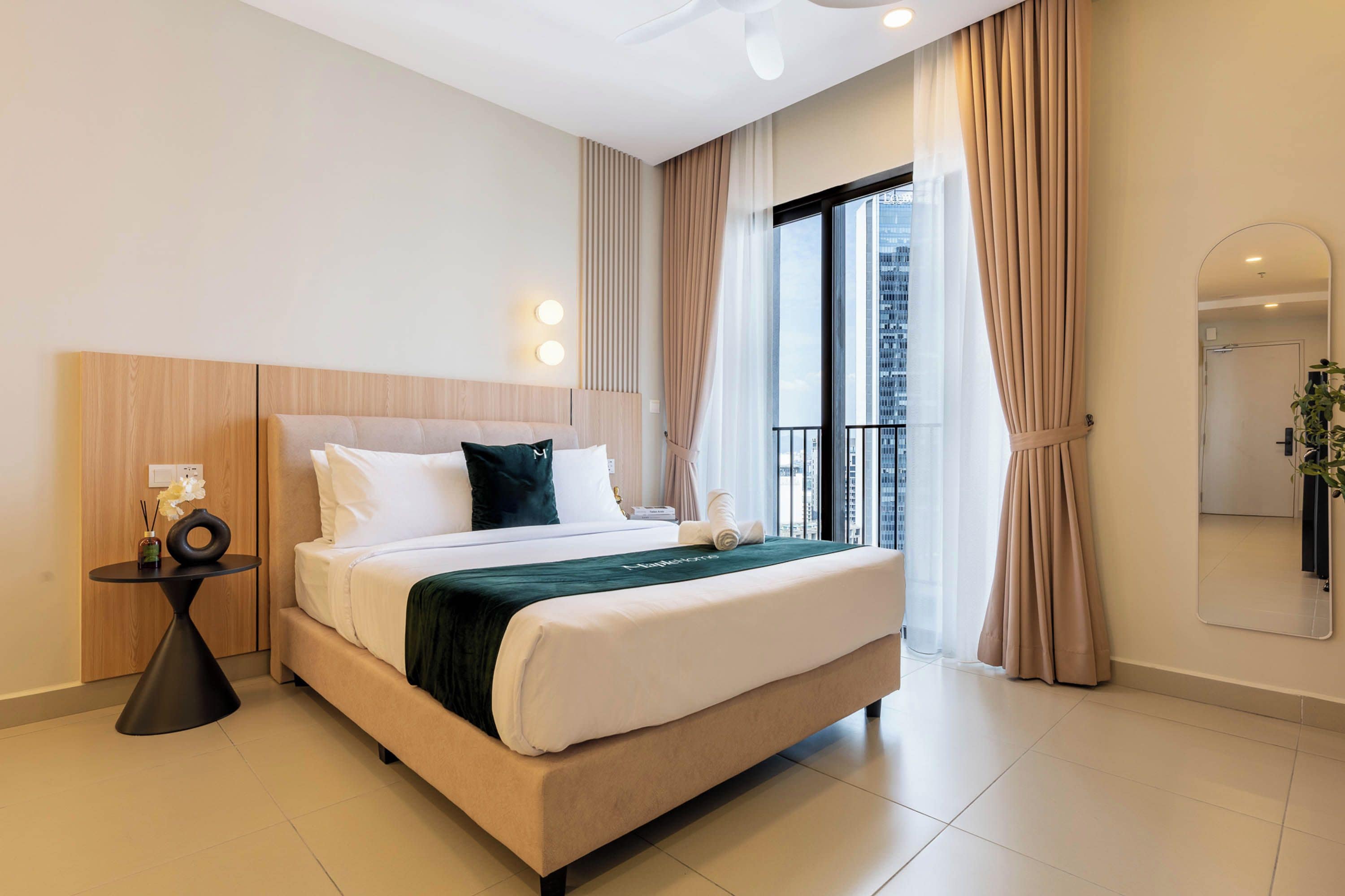 A modern hotel room with a large bed, a bedside table, a mirror, and a view of the city.