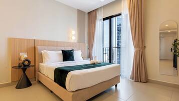 A modern hotel room with a large bed, a bedside table, a mirror, and a view of the city.