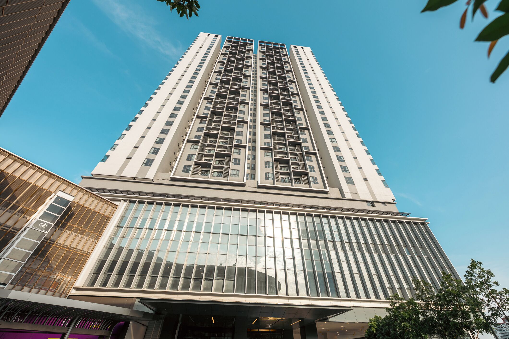 Un immeuble de grande hauteur doté d’une architecture moderne, caractérisé par une façade en verre remarquable et une série de balcons.