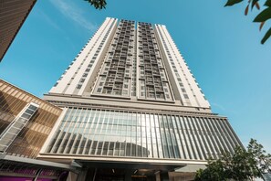 Um edifício alto com design arquitetônico moderno, destacando uma fachada de vidro e uma série de varandas.