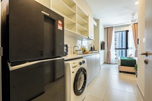 Eine kleine Küche mit Waschmaschine, Kühlschrank und Mikrowelle.