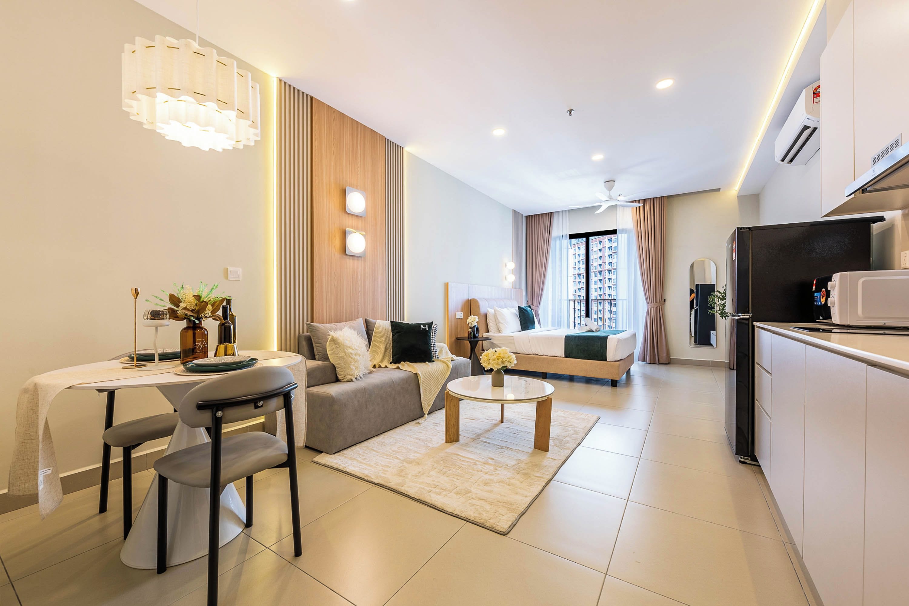 Une chambre d’hôtel moderne et bien éclairée, comprenant un coin repas, un canapé, un lit et un coin cuisine.