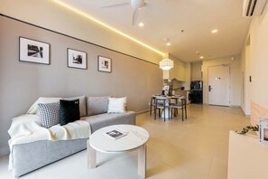 Ein modernes Wohnzimmer mit einem grauen Sofa, einem runden Couchtisch und einem Essbereich mit Tisch und Stühlen.