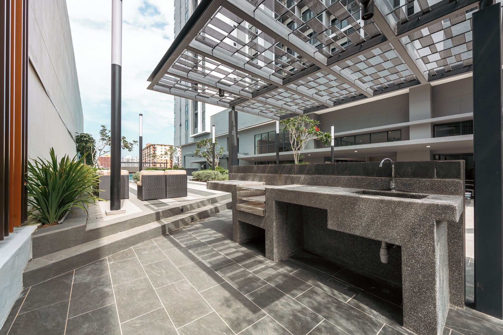 A modern outdoor area with a stone bench, a planter with a tree, and a large window overlooking a cityscape.