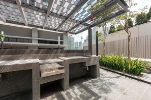 Un espace extérieur aménagé avec un design moderne, comprenant un barbecue intégré et une structure en forme de pergola.