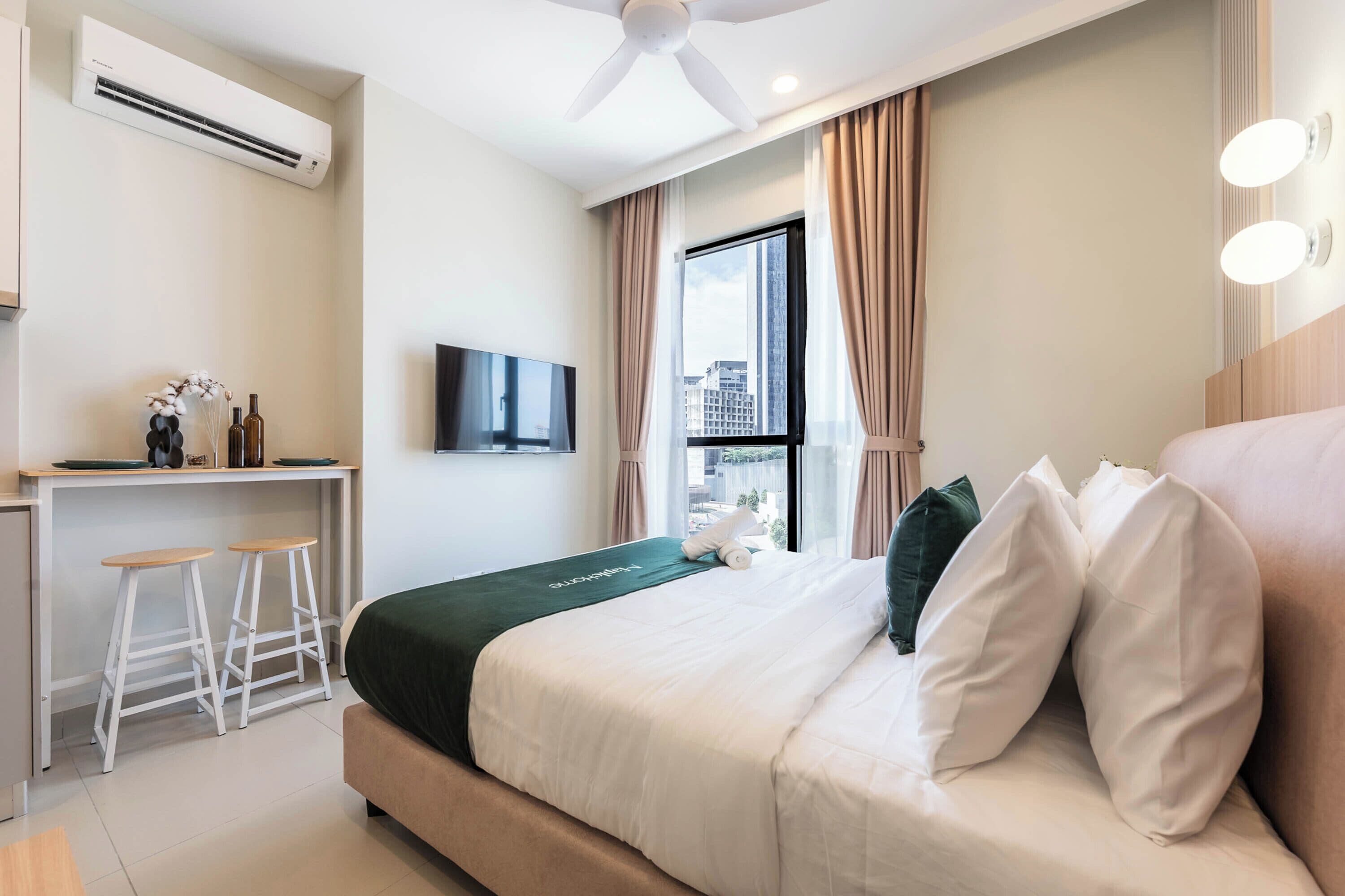 A hotel room with a bed, a desk, a chair, a television, and a window with curtains.