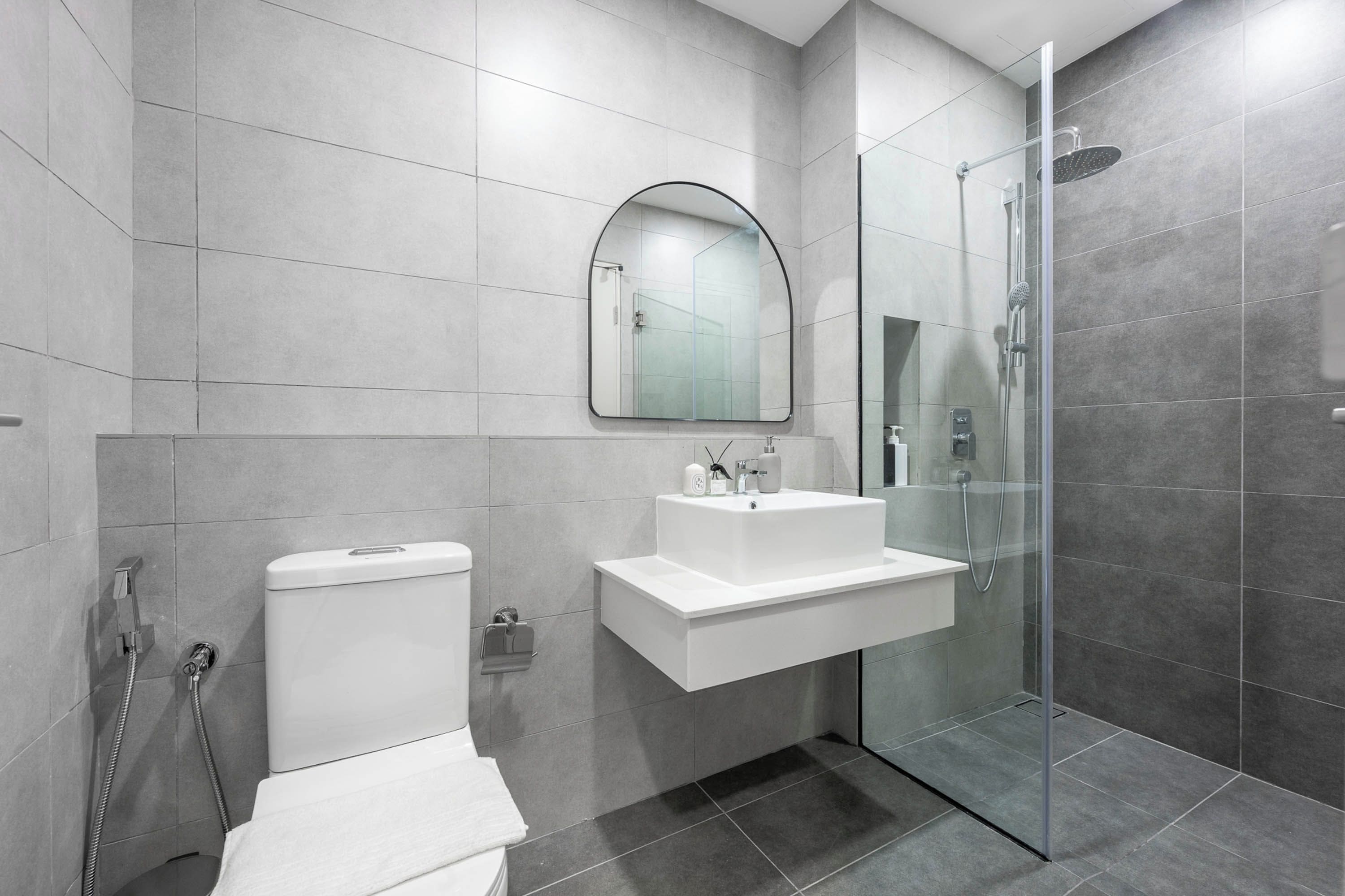 Un baño moderno con inodoro, lavamanos y zona de ducha.