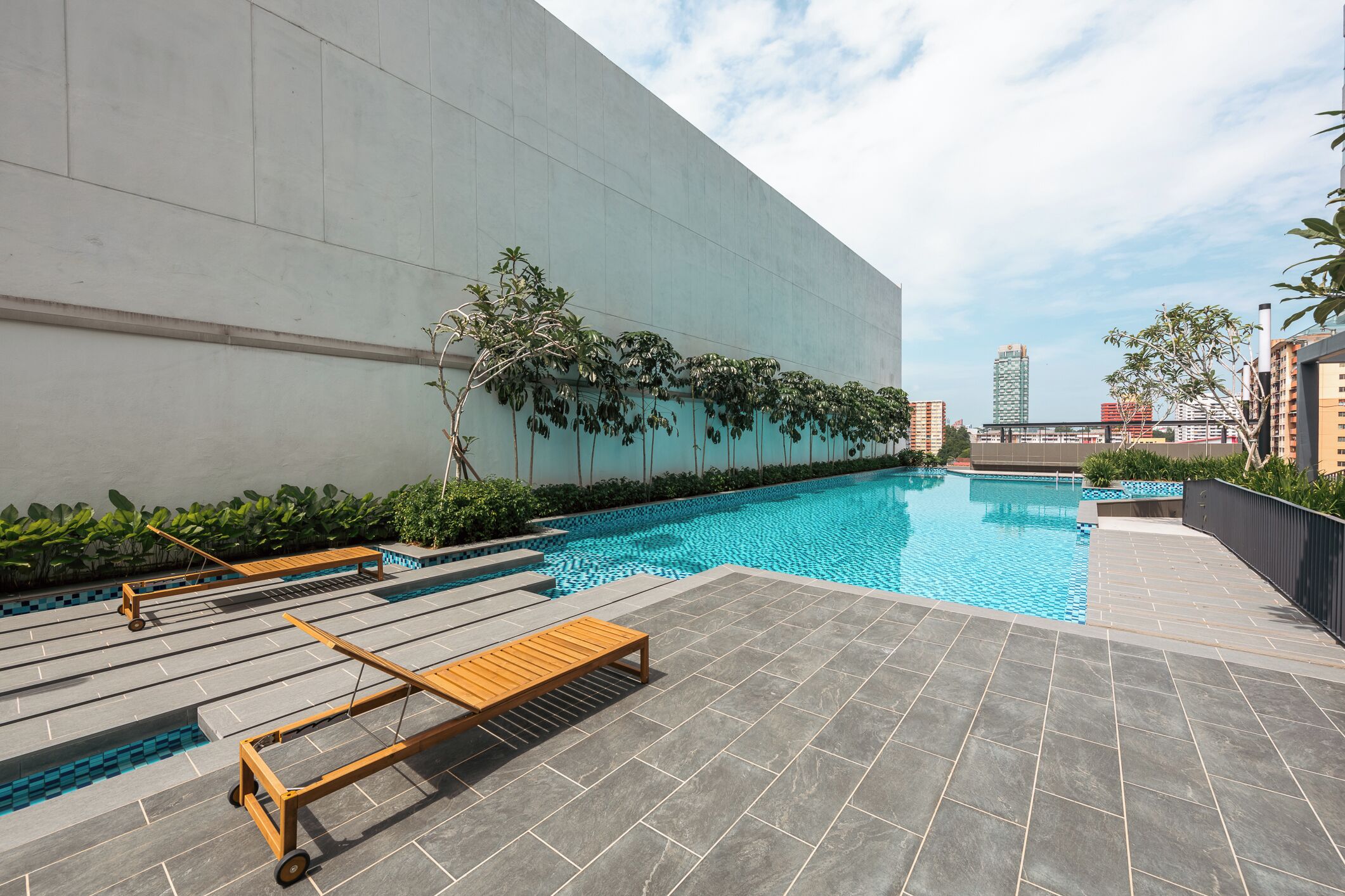 Un área de piscina en la azotea con vistas despejadas del horizonte urbano, incluyendo edificios altos.