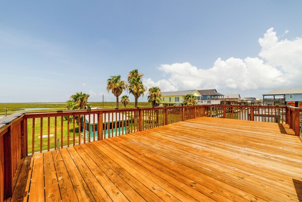 Una terraza de madera con vista a una playa y casas a lo lejos.
