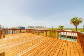 Una terraza de madera con vistas a casas y una palmera.