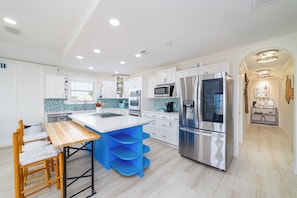 Una cocina moderna con armarios blancos, electrodomésticos de acero inoxidable y una isla azul.