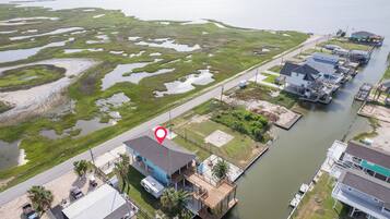 A waterfront property with a dock, a house with a blue roof, and a large body of water with marshy areas.