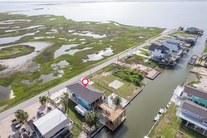 A waterfront property with a dock, a house with a blue roof, and a large body of water with marshy areas.