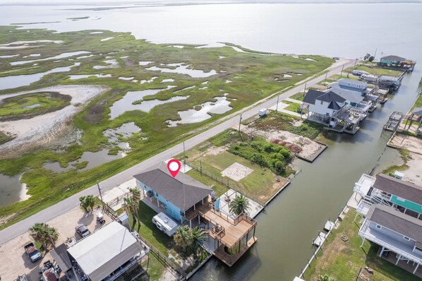 A waterfront property with a dock, a house with a blue roof, and a large body of water with marshy areas.
