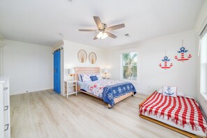 Un dormitorio con una cama, una cama adicional, un ventilador de techo y adornos en las paredes.