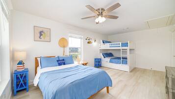 A bedroom with a single bed, a bunk bed, a ceiling fan, a window with blinds, and a wall-mounted lamp.