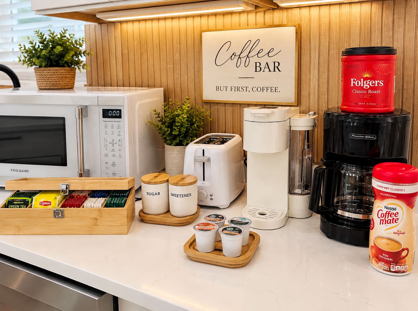 Een koffiebarinrichting met een Frigidaire magnetron, een broodrooster, een koffiezetapparaat en diverse koffiekapsules en verpakkingen.