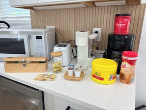 Un plan de travail de cuisine avec un four à micro-ondes, un grille-pain, une machine à café et divers produits alimentaires.