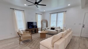 A modern living room with a flat-screen TV, a sofa, a chair, and a coffee table.