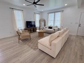 Un salon moderne avec un téléviseur à écran plat, un canapé, un fauteuil et une table basse.