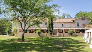 A two-story building with a tiled roof, a covered patio area, and a well-maintained lawn. - Hostellerie Du Clos Pite (Prechacq-les-Bains)