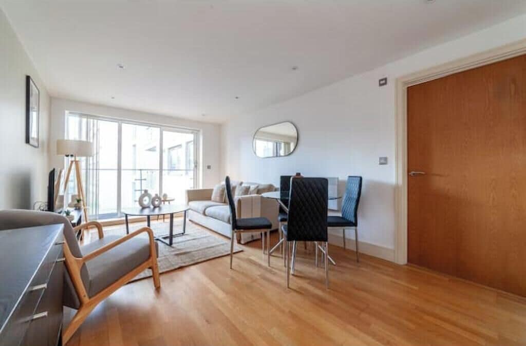 A spacious living area with a sofa, dining table, chairs, and a large window.