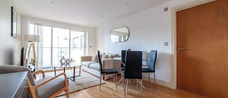 Un vaste espace de vie comprenant un canapé, une table à manger, des chaises et une grande fenêtre.