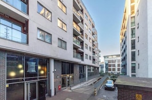 A multi-story residential building with balconies, a ground-level entrance, and a parking area. - Stylish London Bridge Apartment (London)
