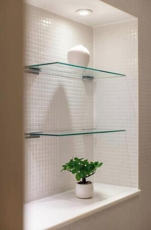 A bathroom with white tiled walls, a glass shelf, and a potted plant. - Stylish London Bridge Apartment (London)
