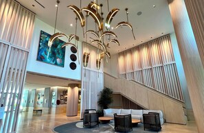 A spacious lobby with a modern chandelier, a large painting, and a staircase leading to upper floors. - 2 bedrooms, 2 baths, luxury, most beautiful beach, Ocean view. 46 nights minimum (Nassau)