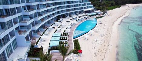 Un hotel moderno con varios balcones, piscina y playa.