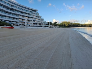 Uma praia com um hotel moderno ao fundo.