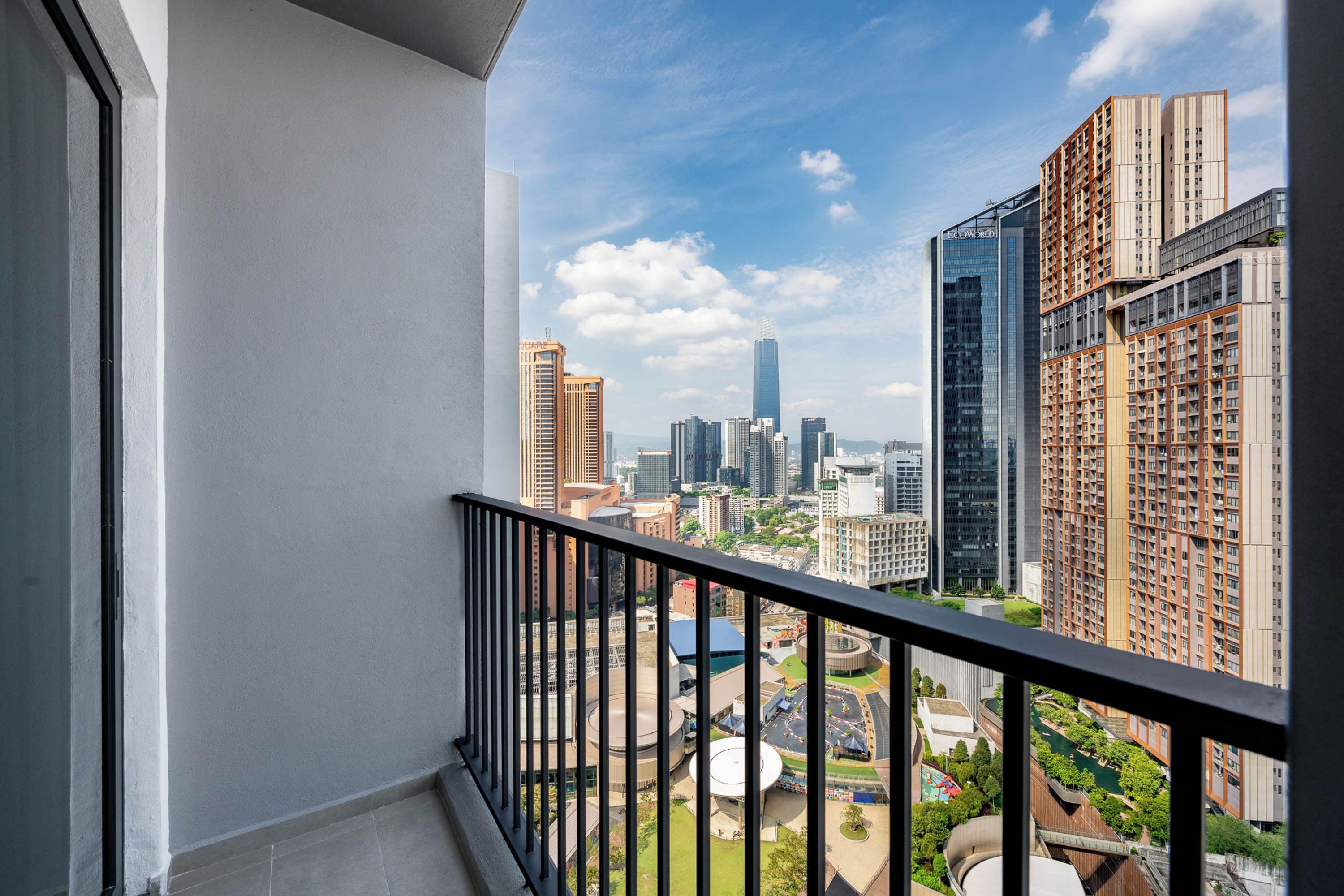 Un balcon offrant une vue sur le paysage urbain, avec des immeubles de grande hauteur et un parc.