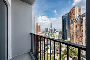 Un balcón con vista a un paisaje urbano que incluye edificios altos y un parque.