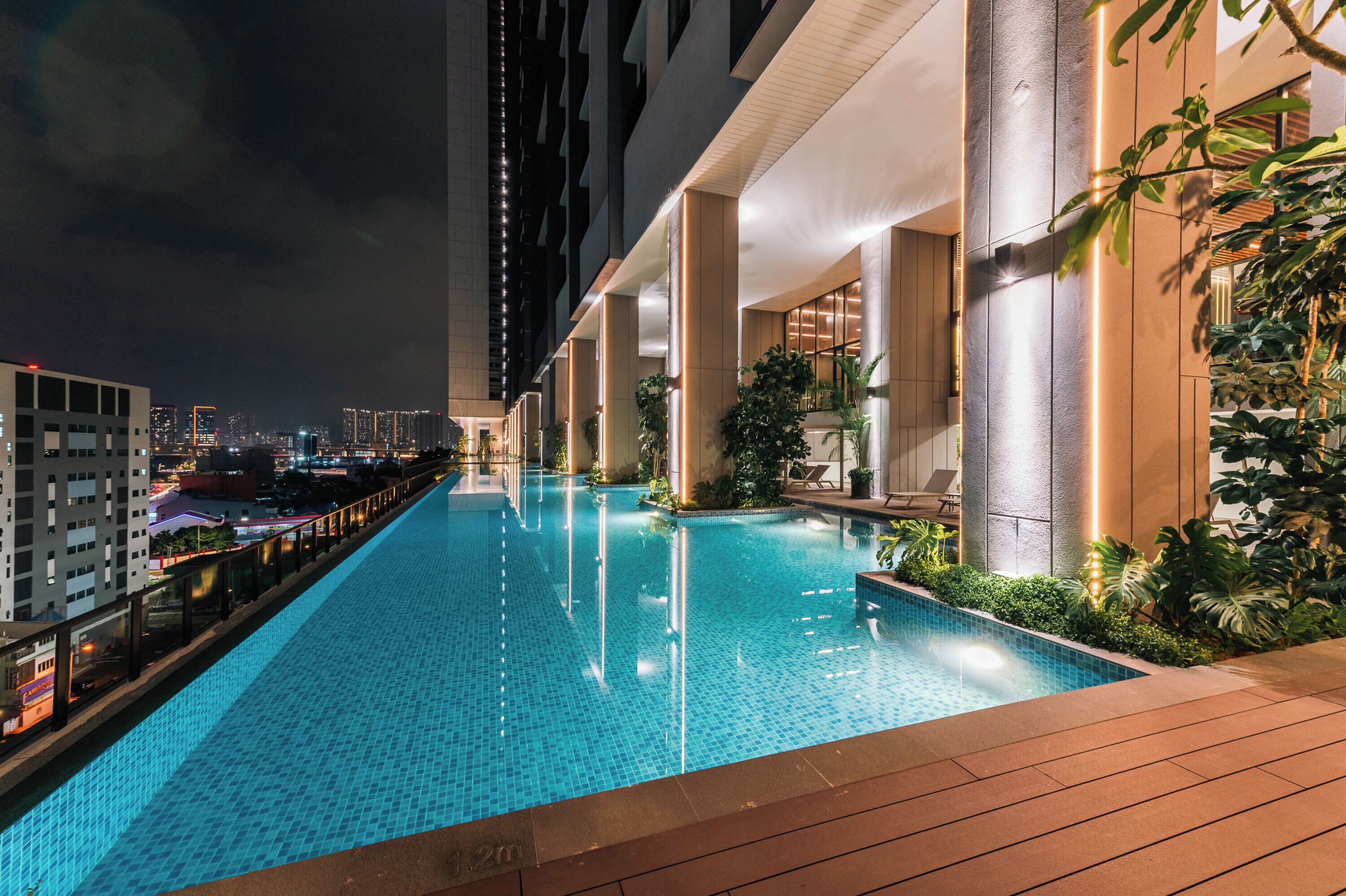 A rooftop infinity pool with a city view, surrounded by modern architecture and plants.