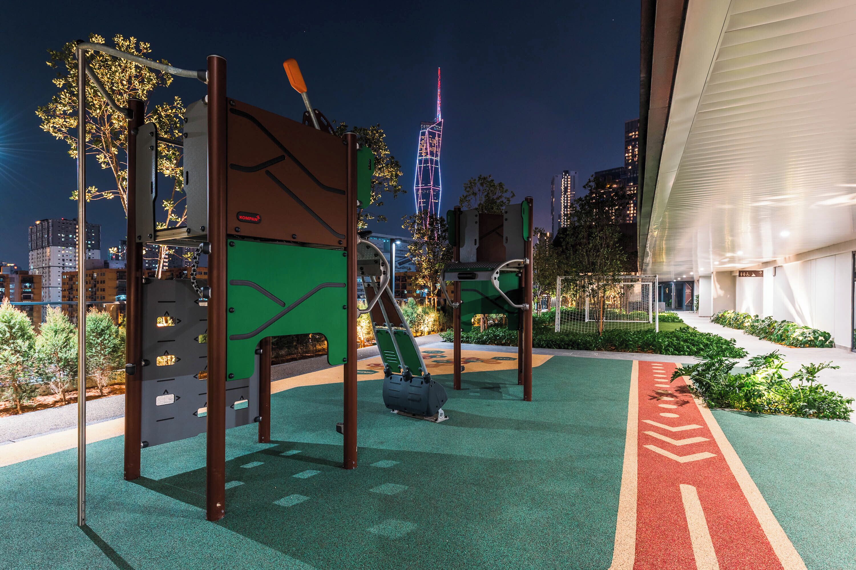 An outdoor playground with climbing structures and a red pathway.