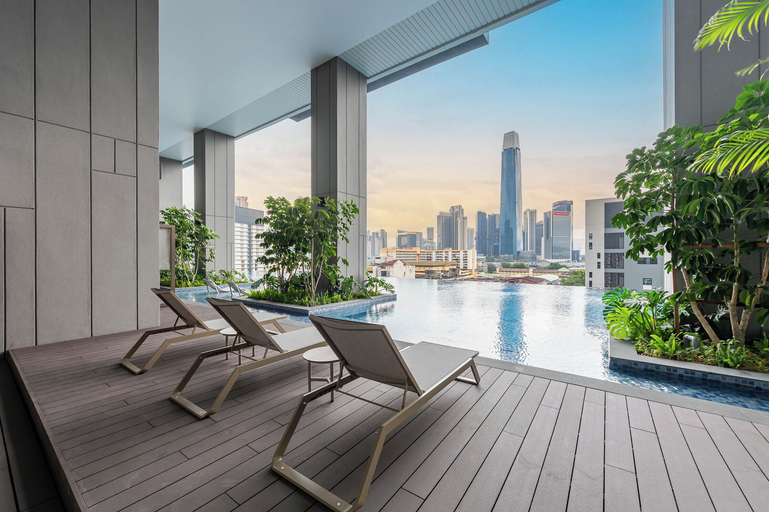 A modern rooftop pool area with lounge chairs and a city skyline view.