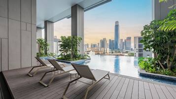 A modern rooftop pool area with lounge chairs and a city skyline view.