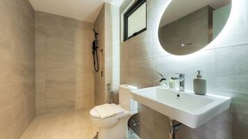 A modern bathroom with a toilet, shower, and sink.