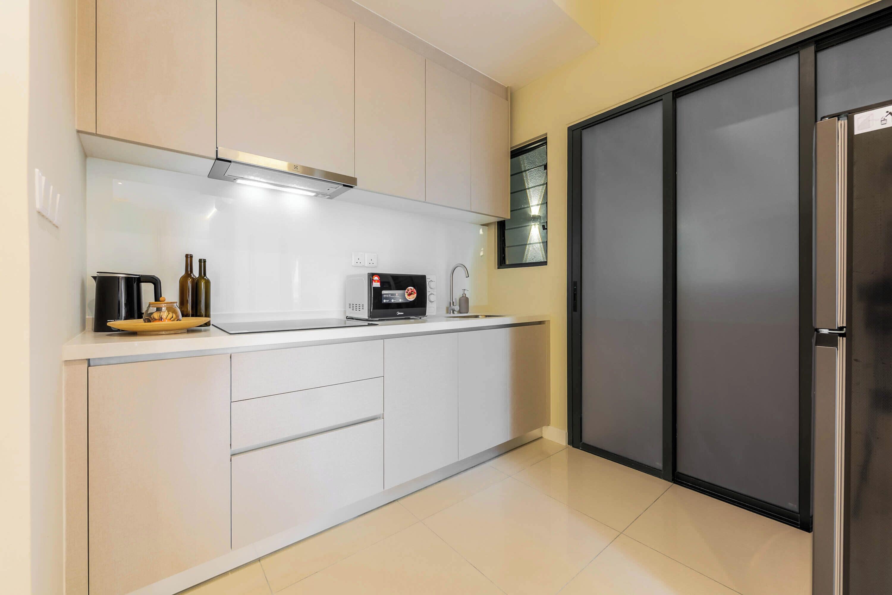 Une cuisine moderne avec des armoires blanches, une hotte de cuisinière en acier inoxydable, un four à micro-ondes encastré et un réfrigérateur à deux portes.