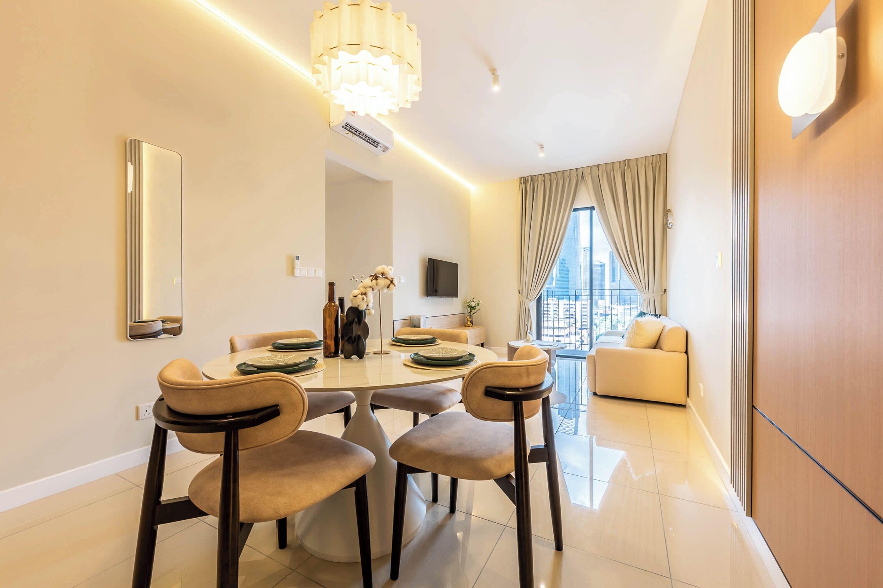 A modern dining area with a round table, four chairs, and a chandelier.
