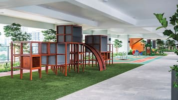 Un área de juegos interior moderna con una estructura de madera para escalar y césped artificial.