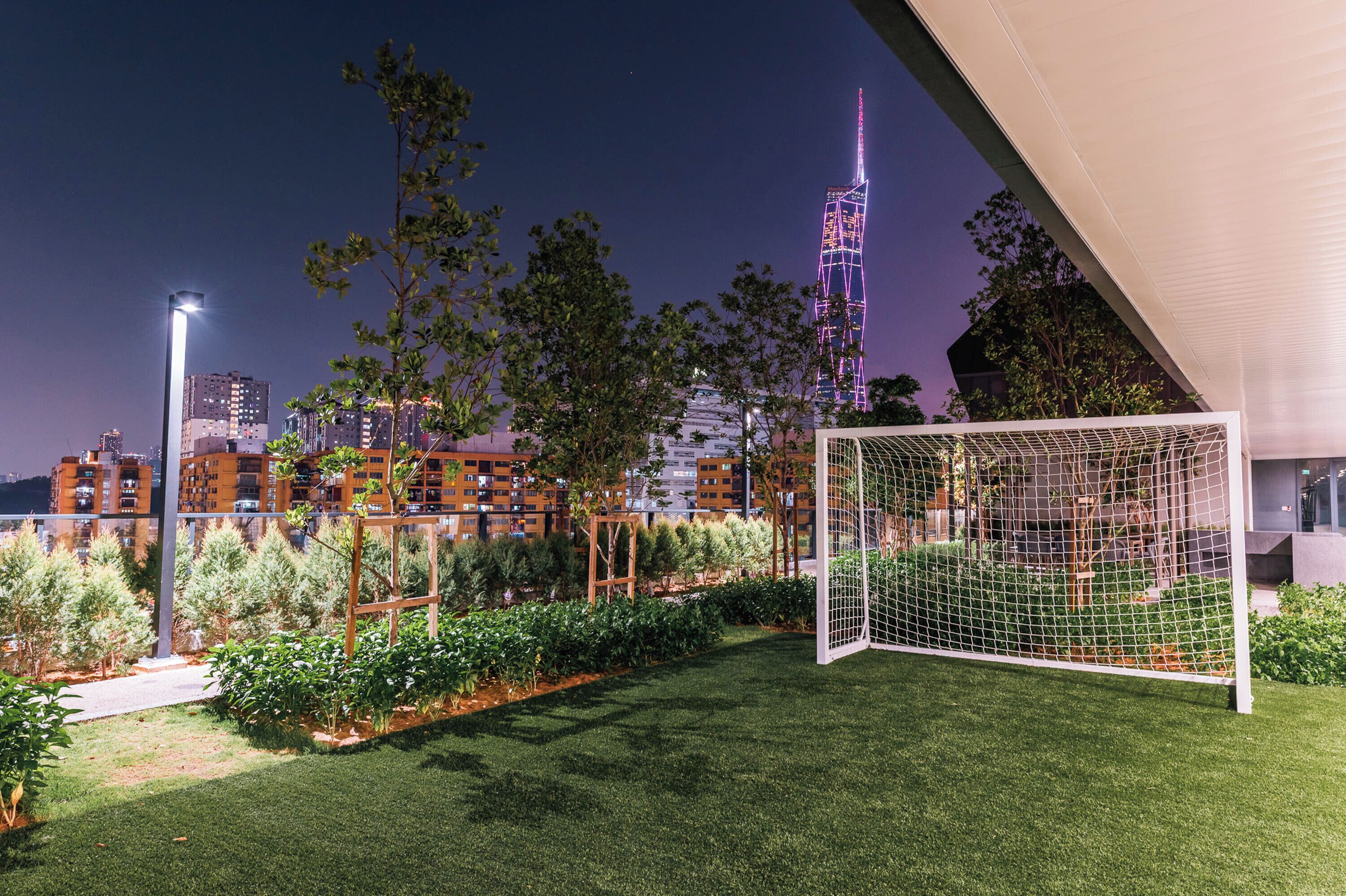 A well-maintained garden with a soccer goal, surrounded by neatly trimmed grass and various plants.